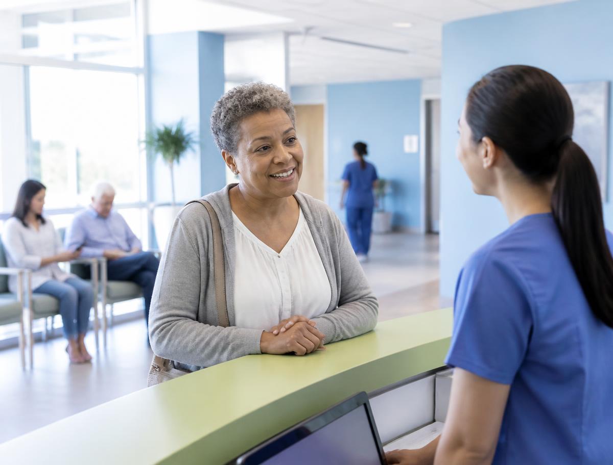 A patient speaking with a nurse at a community health clinic front desk
